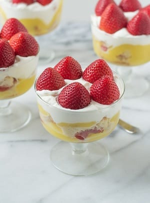 strawberry short cakes in small bowls with strawberries around the top 