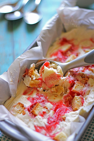 strawberry ice cream cake in a baking pan with an ice cream scooper scooping some out 