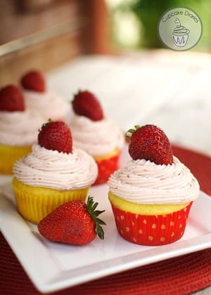 strawberry lemon cupcakes with strawberry frosting and a cherry on top on a white plate 