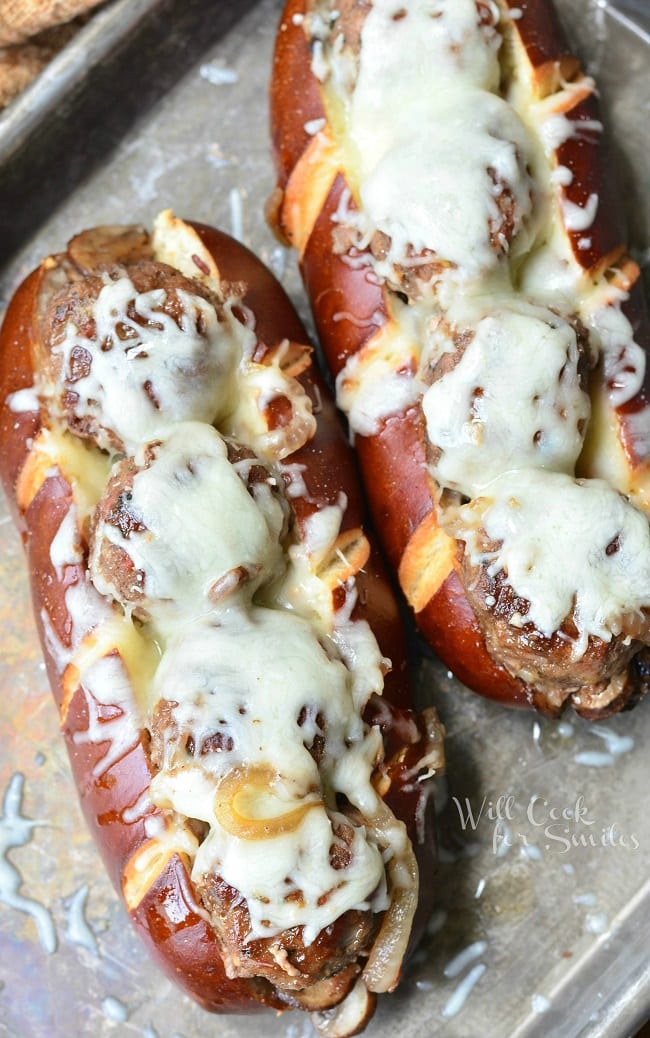 Top view of these Bacon Buffalo Meatball Subs. The juicy meatballs are lined up in a soft pretzel sub roll, baked with sauteed onions, mushrooms and bacon and topped with lots of mozzarella cheese.