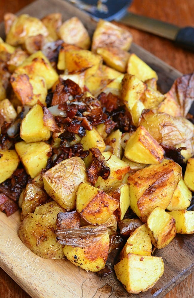 Brown Butter Roasted Potatoes with Bacon and Pearl Onions on a cutting board 