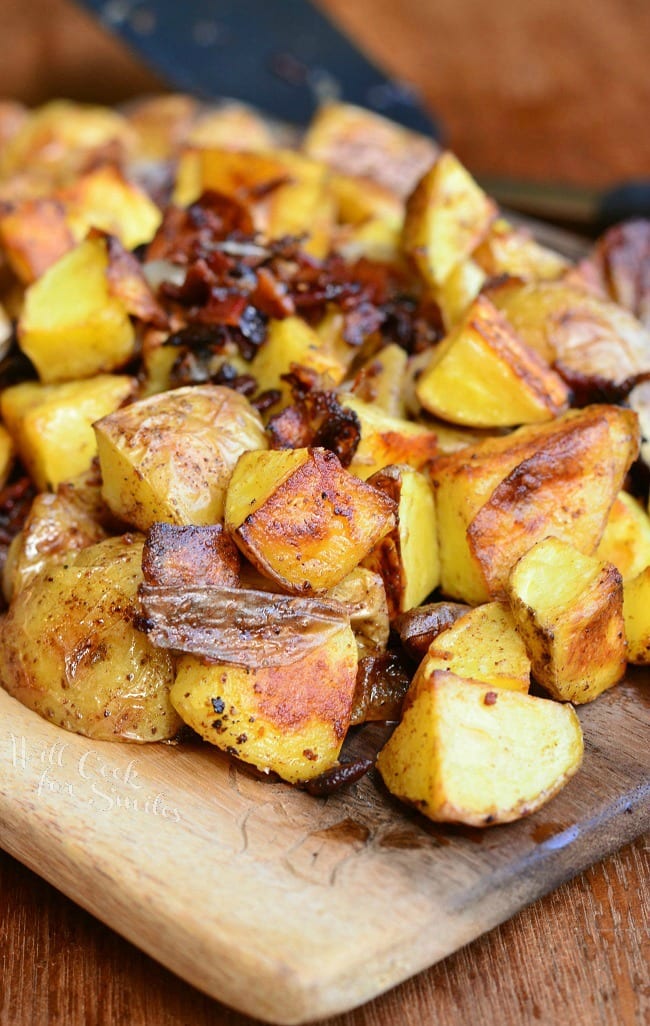 Roasted Potatoes with Bacon and Pearl Onions on a wood cutting board 