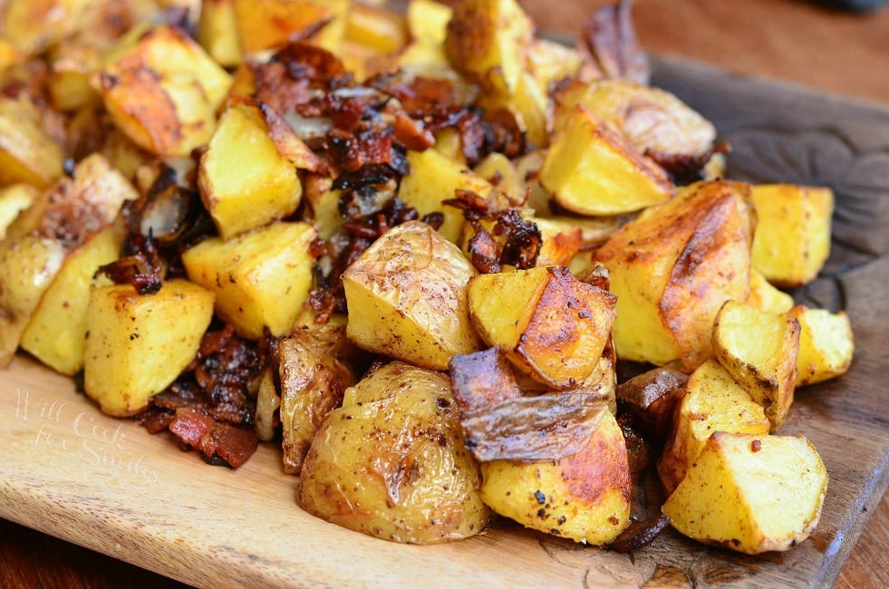 Roasted Potatoes with Bacon and Pearl Onions on a wood cutting board 