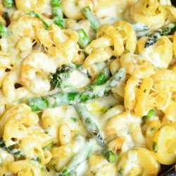 black skillet filled with extra cheesy lemon aspaus pasta on a white and yellow towel on a wooden table as seen from above