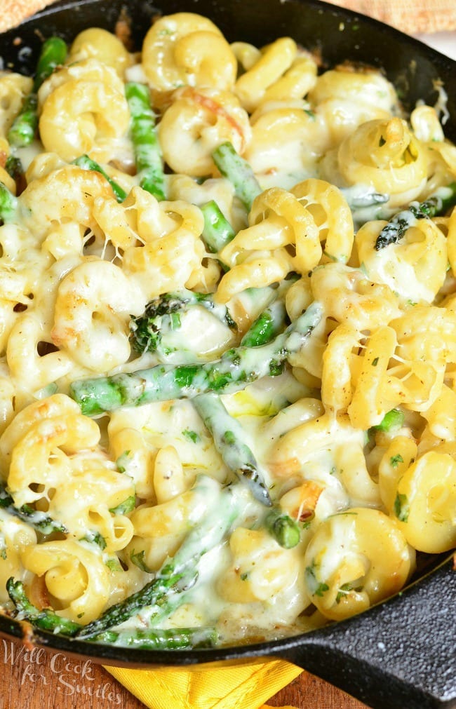 Top view of Extra Cheesy Lemon Asparagus Pasta Skillet in a black skillet. In the skillet, there are many noodles and asparagus covered in a creamy sauce.