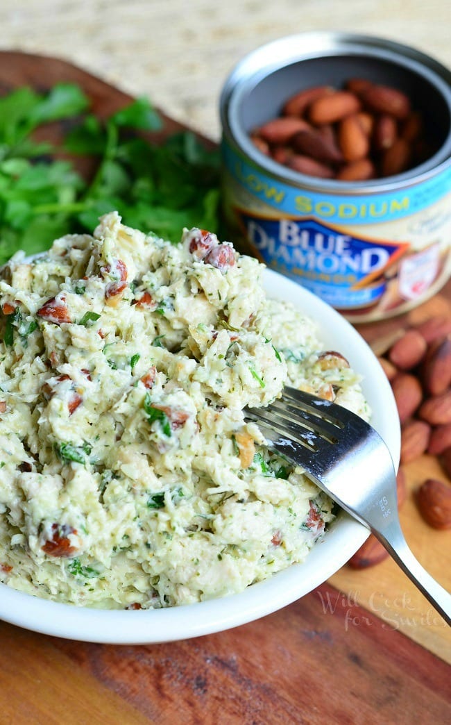 Italian Three Cheese Chicken Salad in a white bowl with a fork laying to the right side and a can of blue almonds in the background 