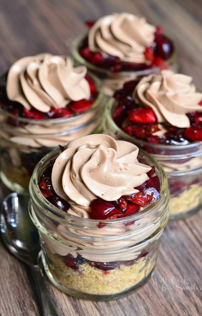 four Chocolate Cherry Cheesecake Pies In A Jar on a wood table 