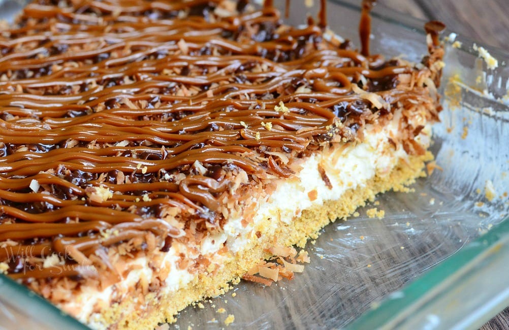 Samoas Cheesecake Bars with caramel and toasted coconut on top on a white plate 