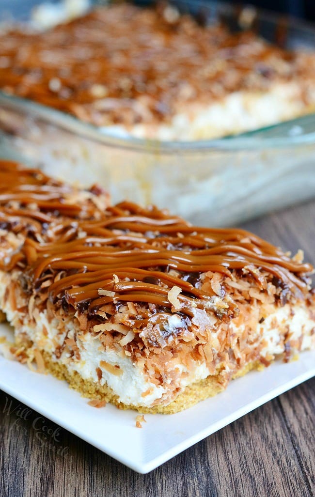 Samoas Cheesecake Bars with caramel and toasted coconut on top on a white plate 