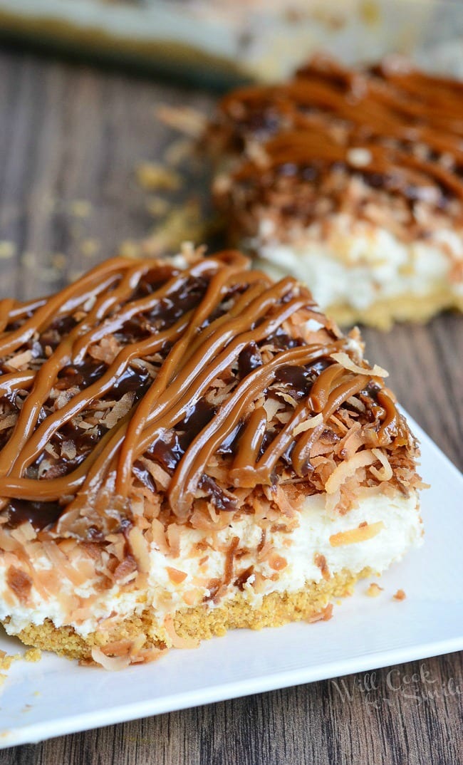 Samoas Cheesecake Bars with caramel and toasted coconut on top on a white plate 