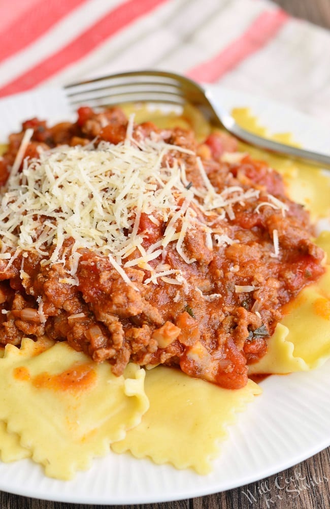 Ravioli with Meat Sauce with parmesan cheese on a white plate  with a fork to the back 