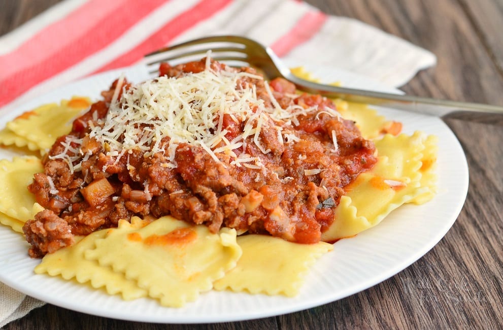 Ravioli with Meat Sauce with parmesan cheese on a white plate with a fork to the back 