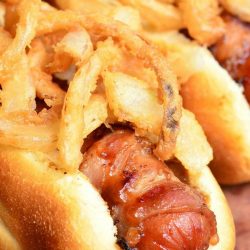 close up view of bbq bacon crsipy onion hot dogs on a wooden table