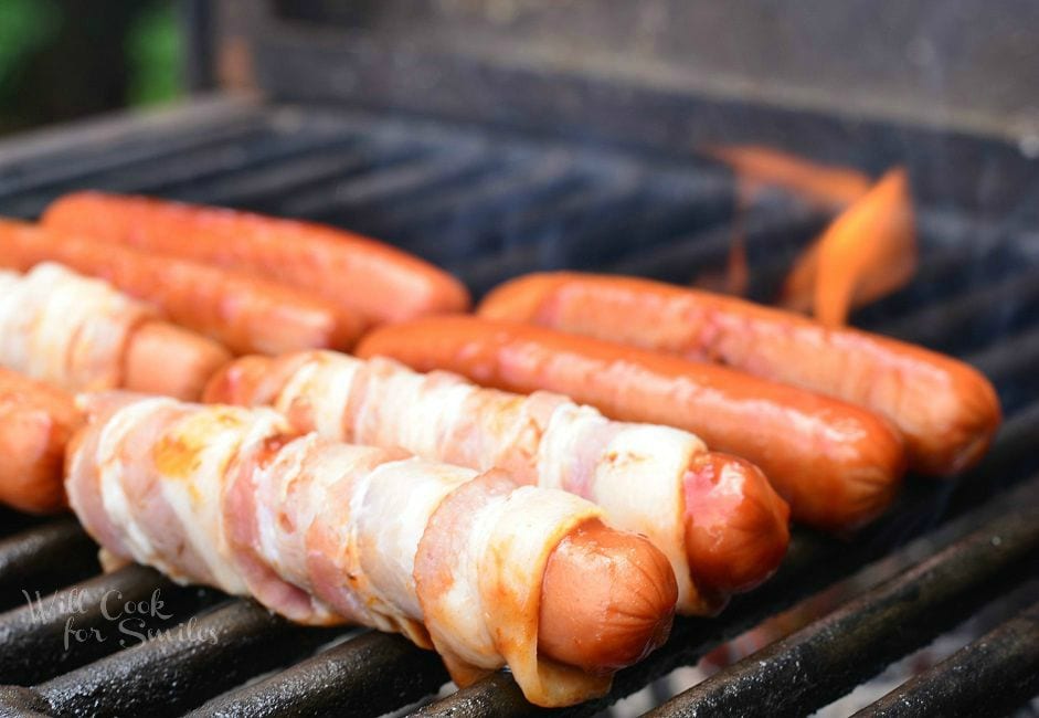 hot dogs on the grill wrapped in bacon