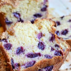 2 slices of cherry streusel bread in front of rest of loaf on a wooden table