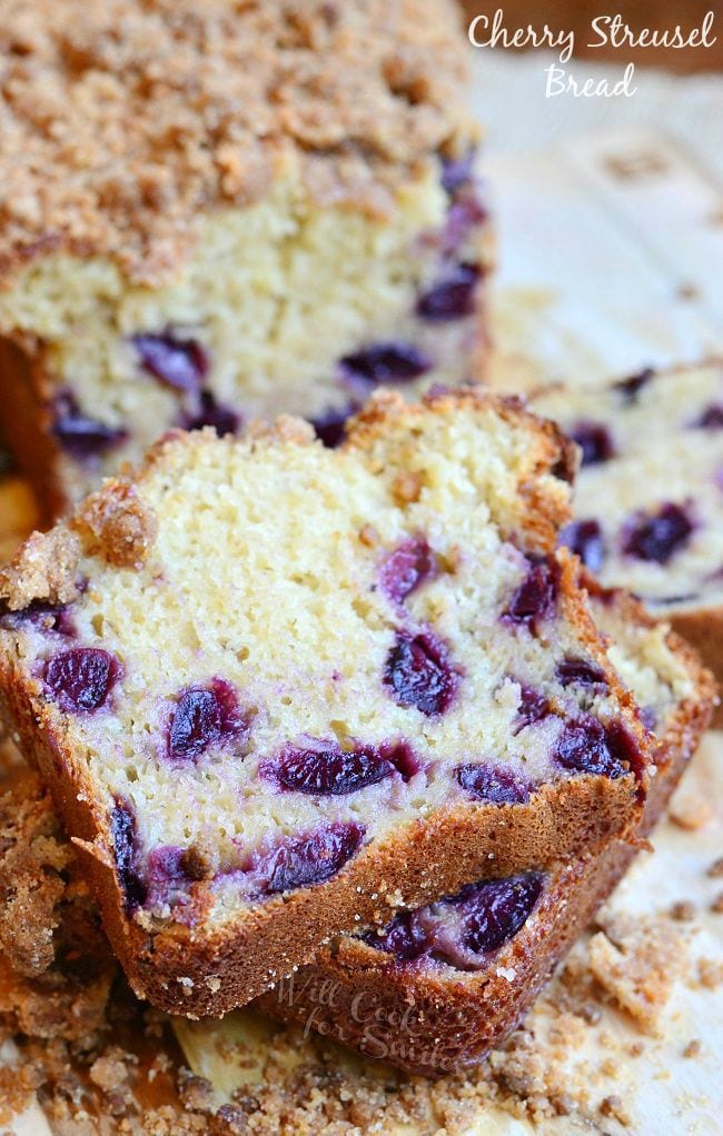 2 slices of cherry streusel bread in front of rest of loaf on a wooden table