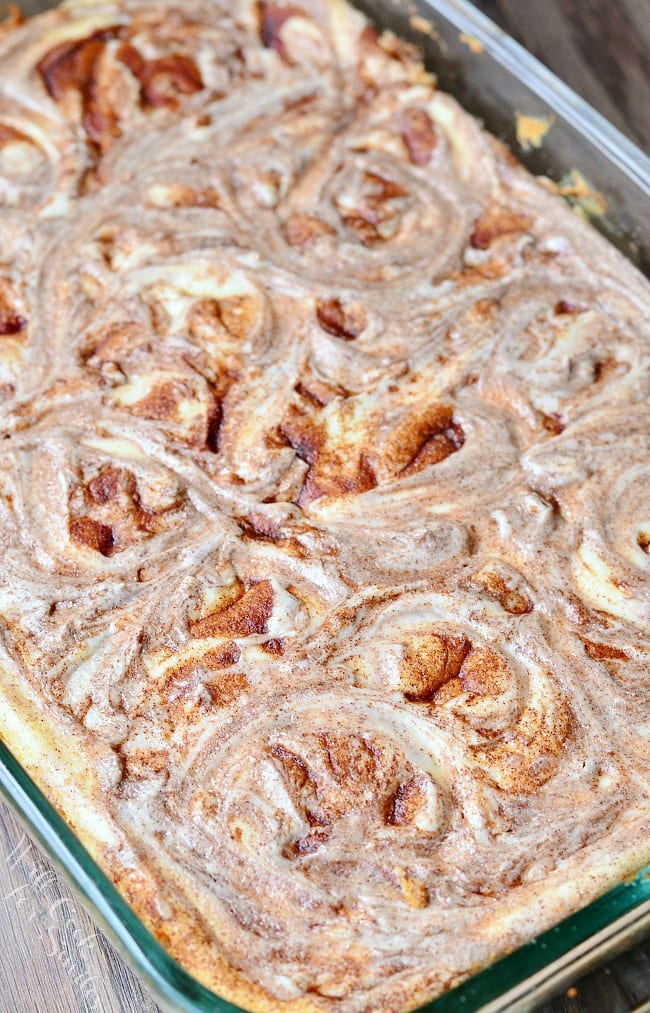 Top view of cheesecake Bars in a glass baking dish. There are swirls on top of the cheesecake where the cinnamon mixture has been swirled into the cheesecake mixture.