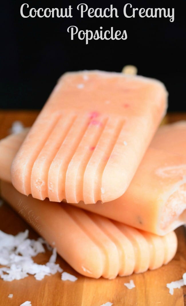 Coconut and Peach Creamy Fruit Ice Pops staked on a cutting board with coconut around it 