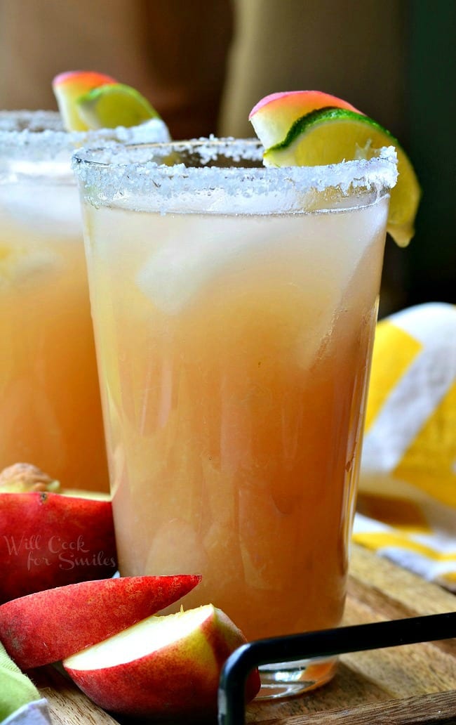 White Peach Margarita in a glass with a salted rim and a peach and lime as garnish 