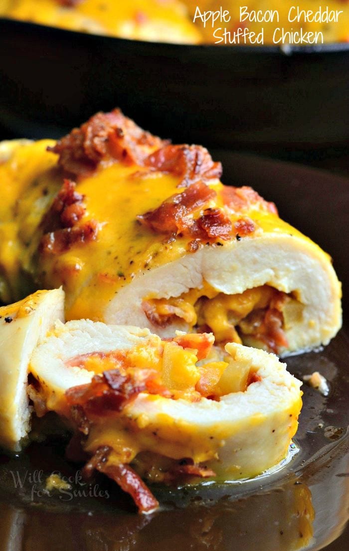 Sliced chicken breast that's been stuffed with apples, bacon, and cheese. Melted cheese and bacon also appear on top of the chicken breast.