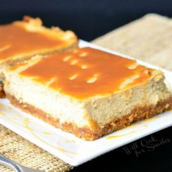 2 portions of caramel macchiato cheesecake bars on a white rectangular plate with a fork n the foreground