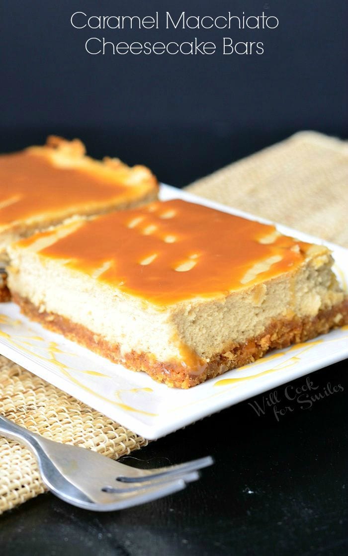 Caramel Macchiato Cheesecake Bars are on a white plate. Caramel is drizzled on top of the bars, as well as on the plate. A fork is laid to the left side of the plate.