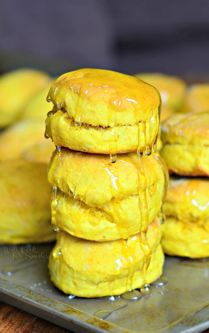 stacks of honey pumpkin biscuits on a metal sheet tray on a wooden table as viewed close up