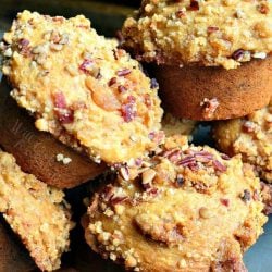 baking pan with maple bacon streusel muffins with strips of bacon below muffins and a muffin pan in the background viewed close up