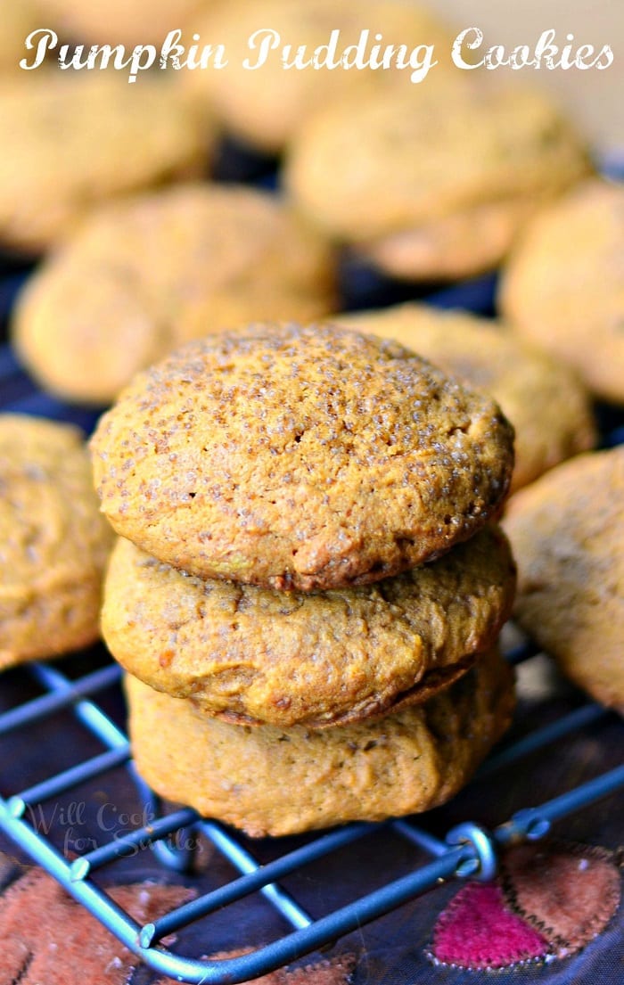 3 pumpkin pudding cookies stacked on a wire cooling rack with more cookies in the background