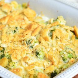 white baking dish filled with broccoli cheese chicken on a wooden cutting board