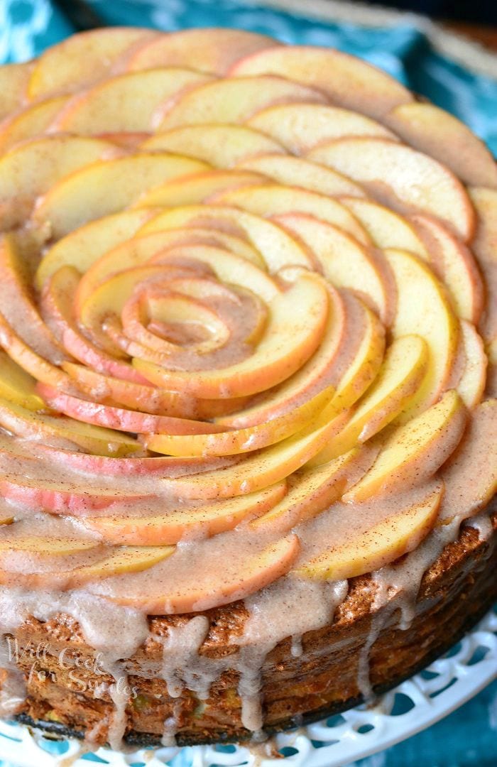picture of a whole cinnamon glazed apple cake on a white cake presenter as viewed from above