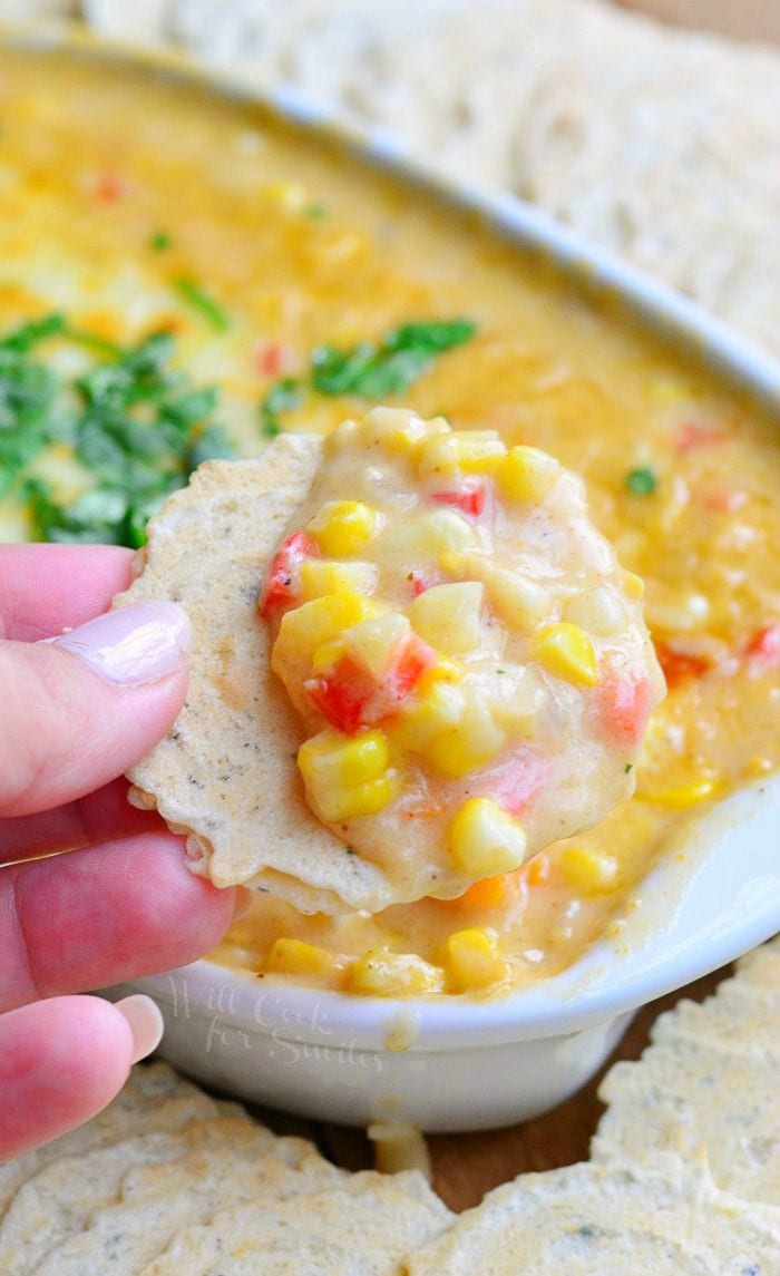 holding a Corn Chowder Hot Dip on a cracker with corn and peppers 