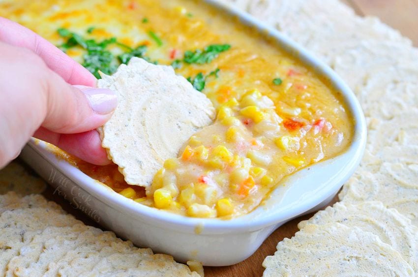 dipping cracker in Corn Chowder Hot Dip with crackers around the naking dish 