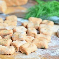 picture of uncooked homemade tomato herb gnocchi on a rolling mat covered lightly in flour