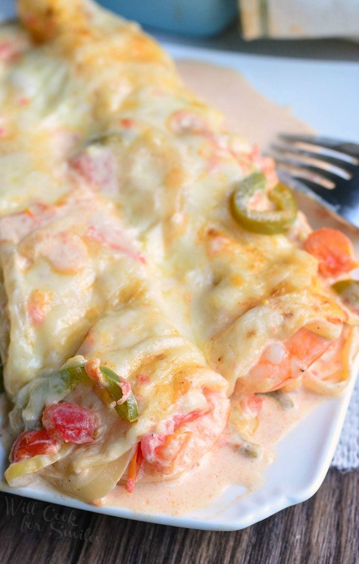Spicy Creamy Shrimp Enchiladas on a plate with a fork to the right side 