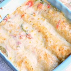 blue baking dish filled with spicy creamy shrimp enchiladas on a white cloth as viewed from above