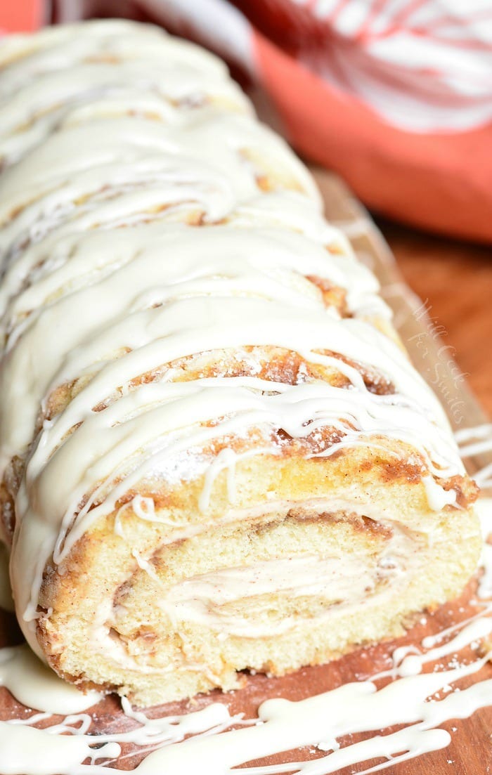 Cinnamon Roll Cake Roll with icing all over the top on a cutting board