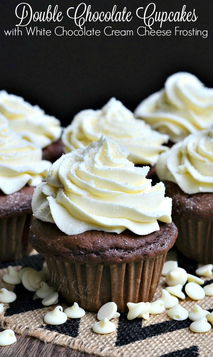 Double Chocolate Cupcakes with cream cheese frosting on a table with white chocolate chips 