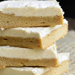 4 frosted maple cookie bars stacked on a tan placemat