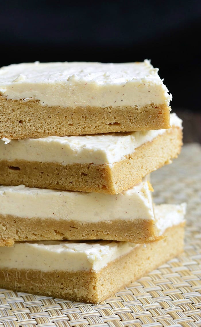 Frosted Maple Cookie Bars stacked up on top of each other on a placemat 