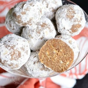 Decorative martini glass filled with pumpkin spice rum balls asviewed from the top with one ball cut in half with a red and white cloth in the background.