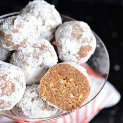 Decorative martini glass filled with pumpkin spice rum balls asviewed from the top with one ball cut in half with a red and white cloth in the background viewed close up