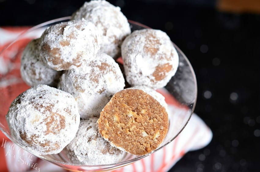 Pumpkin Spice Rum Balls with powder sugar on the outside of them and one with half missing in a champagne glass 