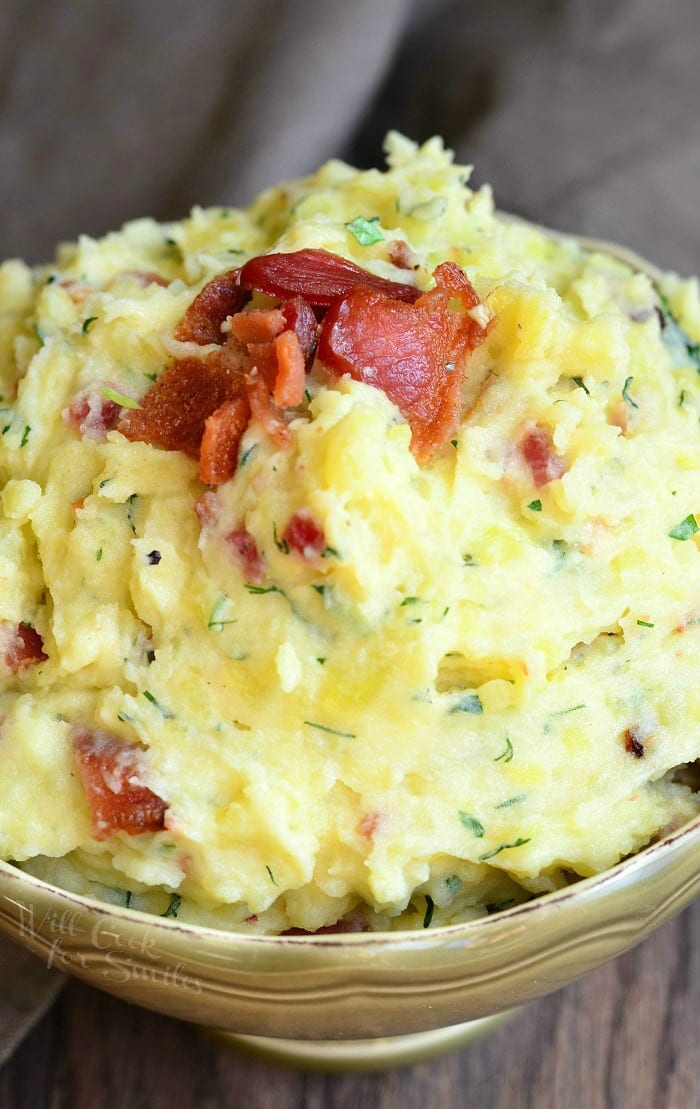 Mashed Potatoes with bacon and herbs mixed in and bacon on top  in a bowl 