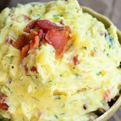 small decorative bowl filled with bacon and herbs creamy mashed potatoes on a wooden table as viewed from above and close up