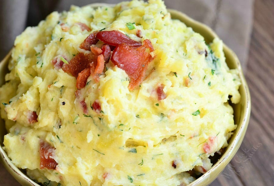 Mashed Potatoes with bacon and herbs mixed in and bacon on top  in a bowl 