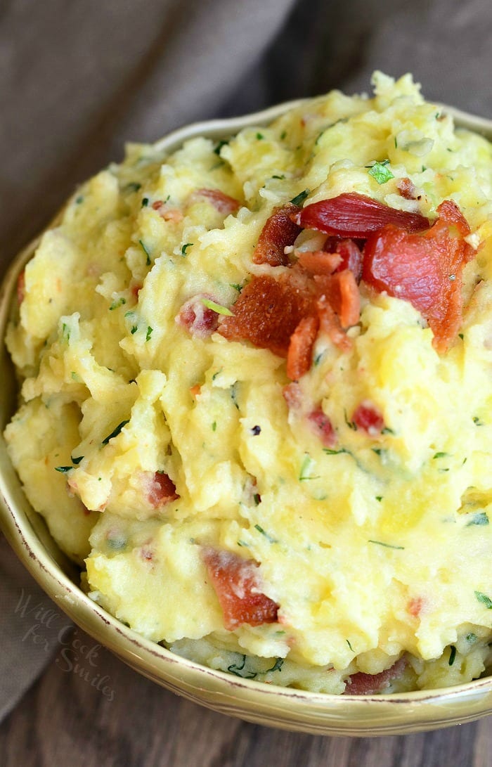Mashed Potatoes with bacon and herbs mixed in and bacon on top  in a bowl 