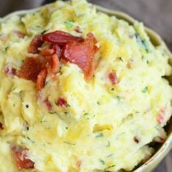 small decorative bowl filled with bacon and herbs creamy mashed potatoes on a wooden table