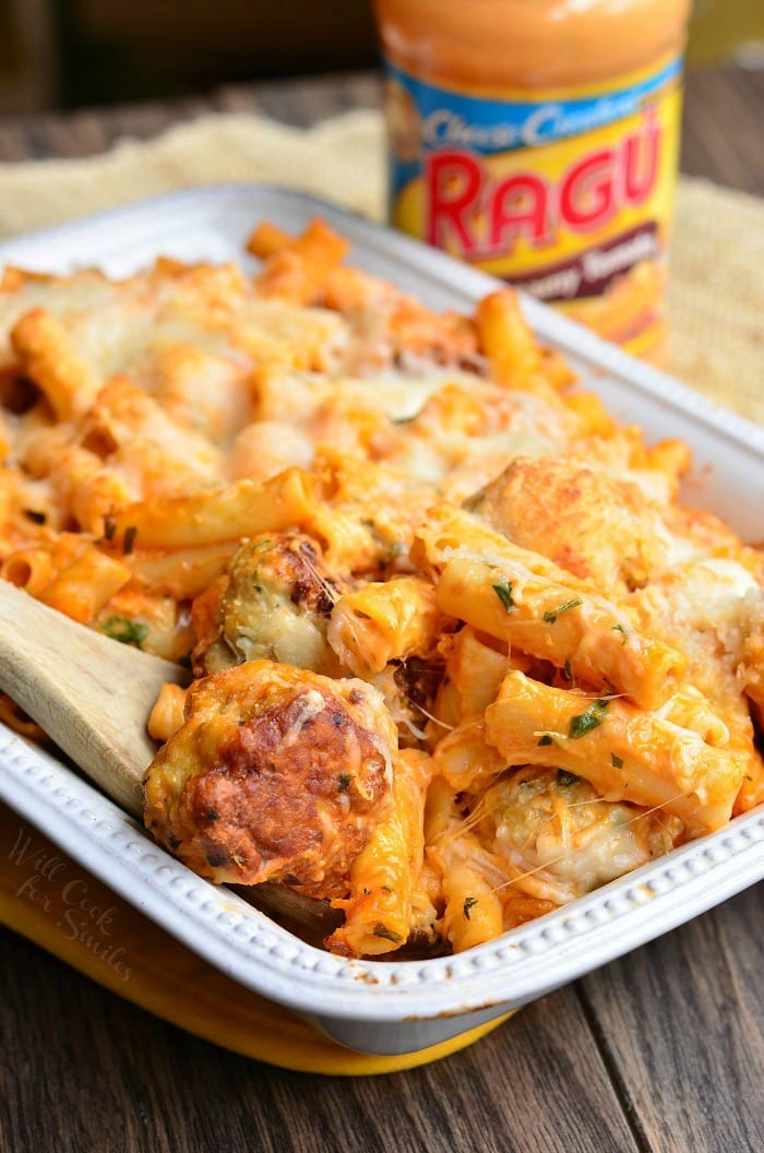 Chicken Meatball Baked Ziti in a white casserole dish with a wooden spoon and jar of pasta sauce in the back ground 