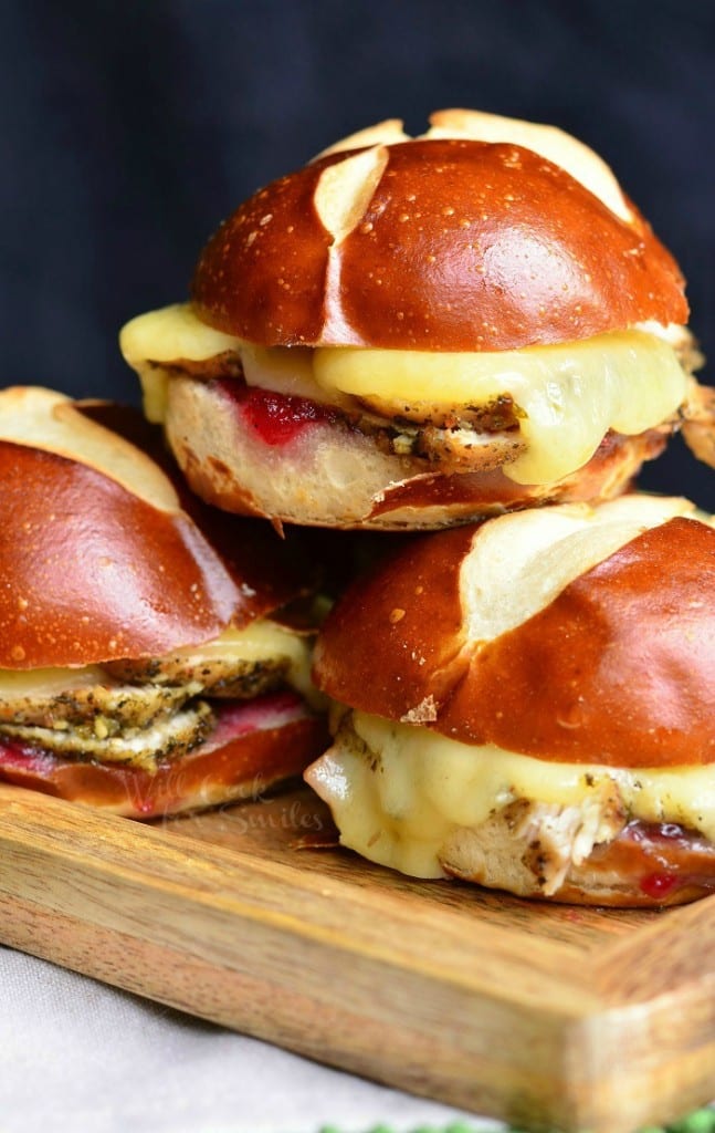 4 cranberry asiago turkey sliders stacked on a wooden cutting board